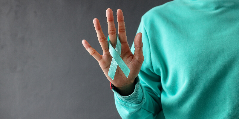 someone adorning a teal ribbon on their finger.