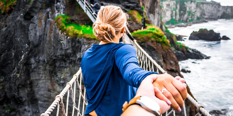 people crossing a walking bridge in nature.