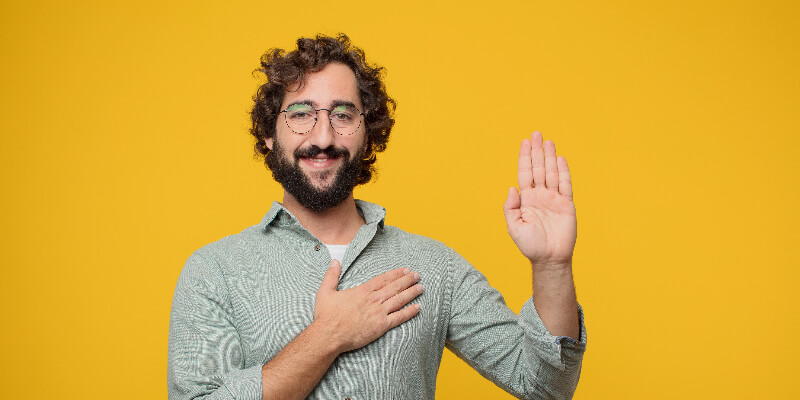 person with right hand over heart and left hand raised at the elbow.