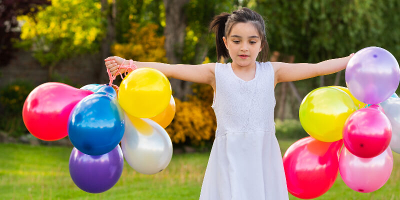 a little girl with balloons in each hand